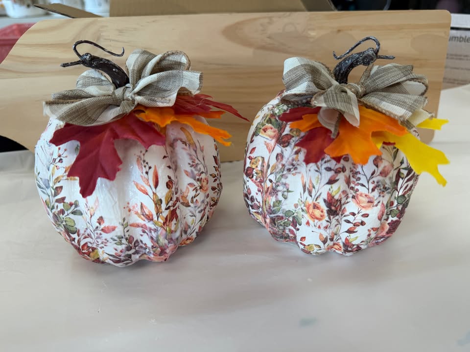 Two decorative pumpkins with floral patterns, fabric bows, and artificial autumn leaves in McLennan County, Texas.