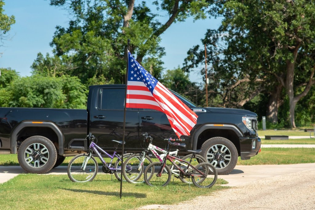 An American flag waves in front of a black pickup truck and two bicycles in McLennan County, Texas.
