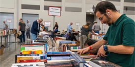 People browsing through tables of books at a large indoor book sale event in McLennan County, Texas.
