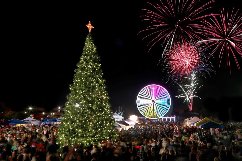 A large crowd gathers at night near a Christmas tree and a lit ferris wheel in McLennan County, Texas.