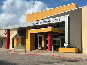 The exterior entrance of the West Waco Library and Genealogy Center on a sunny day in McLennan County, Texas.
