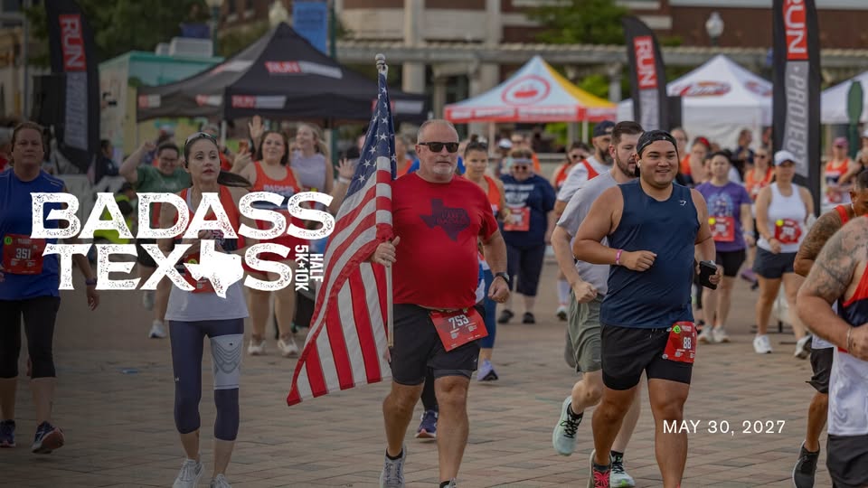 A man carries an American flag while running in a crowded race event in McLennan County, Texas.