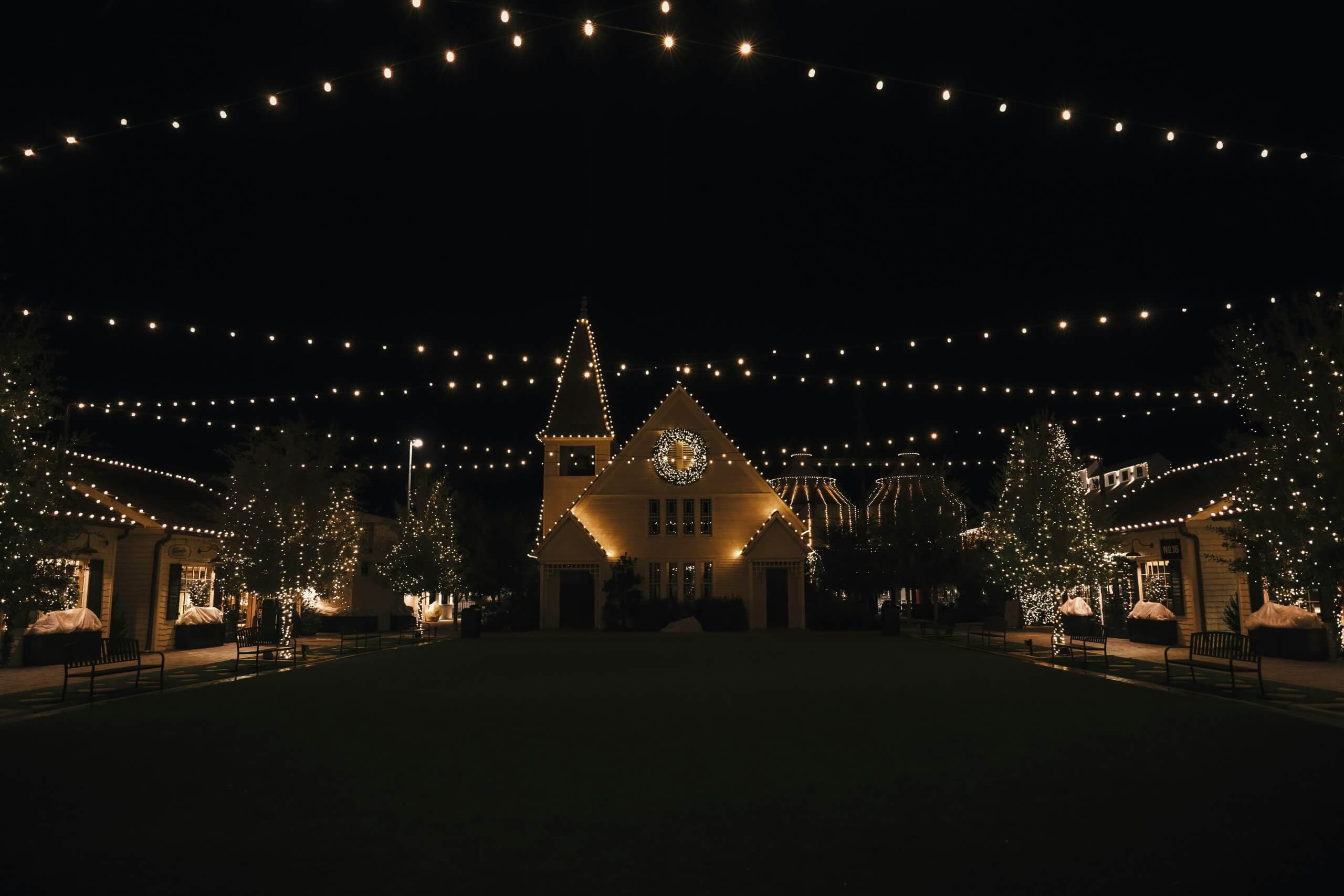 A church building decorated with Christmas lights at night under string lights in McLennan County, Texas.